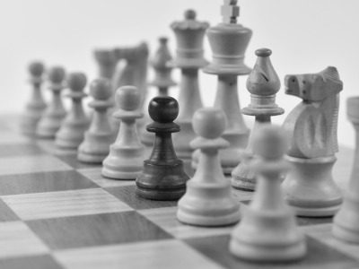 Schachbrett - Gewerblicher Rechtsschutz Schachbrett mit schwarzen und weißen Figuren in strategischer Aufstellung.