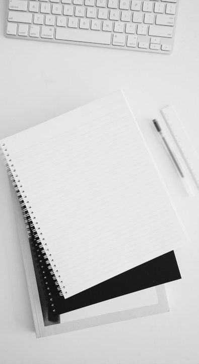 Notizblöcke, eine Tastatur und ein Stift auf einem Tisch.