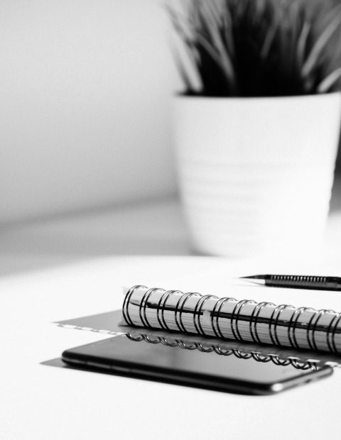 Notizblock - Für Kolleg:innen Schwarzes Smartphone mit Notizblock und Pflanze im Hintergrund.